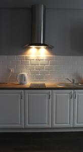 a kitchen counter with a sink and a light at Apartamenty Młynowa in Białystok