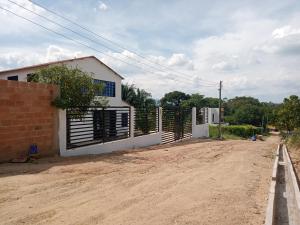 a house with a fence on the side of a dirt road at Casa Cruz Melgar in Melgar
