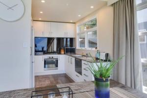 a kitchen with white cabinets and a glass table at The BIGGEST & BEST VIEWS 3 Bedrooms WALK To Town in Queenstown