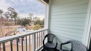 a balcony with two chairs and a large window at Adorable 1BR condo with pool view at Magnolia in Myrtle Beach