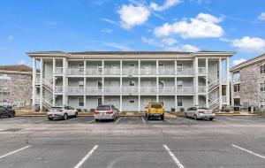 a large apartment building with cars parked in a parking lot at Adorable 1BR condo with pool view at Magnolia in Myrtle Beach