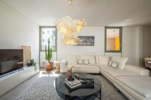 een woonkamer met een witte bank en een kroonluchter bij Award-winning White-spot in Athene