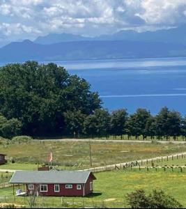 a red barn in the middle of a field at Linda Casa en parcela, 3 minutos de frutillar Bajo in Frutillar