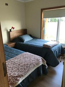 two beds in a bedroom with a window at Linda Casa en parcela, 3 minutos de frutillar Bajo in Frutillar
