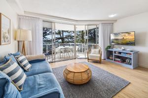 a living room with a blue couch and a table at Zanzibar 406 in Mooloolaba