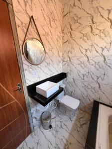 ein Badezimmer mit Waschbecken, Toilette und Spiegel in der Unterkunft Casa nova para alugar em Campina Grande toda mobiliada in Campina Grande + 7 Fotos