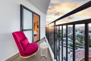 a room with a red chair and a balcony at DQua Hotel in Nha Trang
