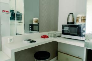 a kitchen with a counter with a microwave and a stove at Nice Studio Apartment at Aeropolis Residence near CGK Airport By Travelio in Tangerang