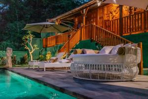 a pool with chairs and an umbrella next to a house at Villa Rosebud in Sukawati