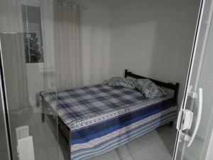 Una cama pequeña en una habitación con puerta de cristal. en Marcos, en Cabo Frío
