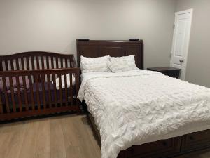 a bed with a white comforter and two cribs in a bedroom at Private Entrance 2 Bed 1 Bath in Winnipeg