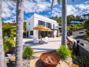 パイヒアにあるVilla Palms Paihiaのヤシの木とパティオのある白い家