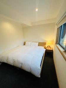 a bedroom with a large white bed with a window at Hakuba Cottage ICHIZAEMON by Jade Group in Hakuba