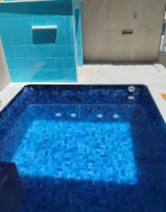 a blue tub in a bathroom with a blue tile wall at Casa Balneário Arpoador in Peruíbe