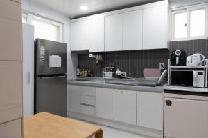 a kitchen with white cabinets and a stainless steel refrigerator at Manoa Garden in Seoul