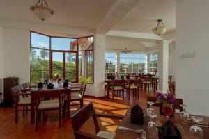 a dining room with tables and chairs and windows at Palazzo Lake Gregory in Nuwara Eliya
