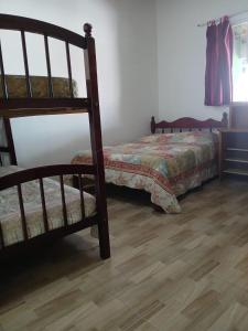 a bedroom with a bed and a wooden floor at Casa para temporada Peruíbe - SP in Peruíbe