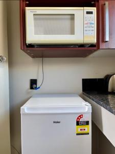 Un microondas encima de un refrigerador en una cocina. en Heart of Christchurch City Studio, en Christchurch