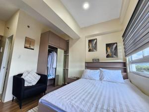 a bedroom with a bed and a chair and a window at Elegant Studio with balcony unit 625 - 6th floor - near Ateneo De Cebu - High speed internet - Northwoods Place in Mandaue City +35 photos