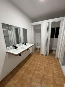 La salle de bains est pourvue de 2 lavabos, d'un miroir et de toilettes. dans l'établissement Apartamento de habitaciones privadas en el centro de Málaga, à Malaga