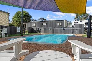 a swimming pool in a yard with two chairs and an umbrella at Crows Nest Tourist Park in Crows Nest