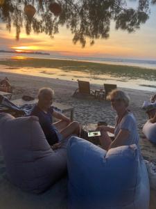 a group of people sitting on the beach watching the sunset at La Bohème in Gili Air