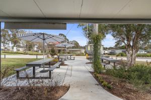 a group of benches with an umbrella in a park at Crows Nest Tourist Park in Crows Nest