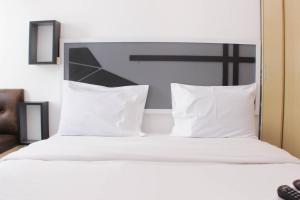 a bed with white sheets and pillows in a room at Cozy and Nice Studio at Sayana Bekasi Apartment By Travelio in Bekasi +15 photos
