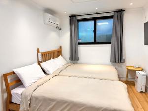 two beds in a small room with a window at Studio 6 in Seoul