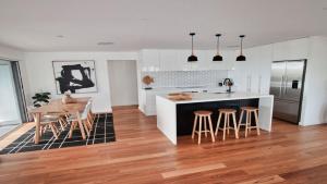 a kitchen with a counter and a table and chairs at The Pool House - Light and Spacious in Wamberal