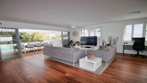 a living room with two couches and a television at The Pool House - Light and Spacious in Wamberal