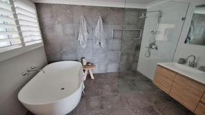 a bathroom with a white tub and a sink at The Pool House - Light and Spacious in Wamberal +8 photos