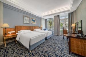 Good View Hotel Tangxia - 15 mins drive from Dongguan South Railway Station في دونغقوان: غرفة فندقية بأربعة أسرة ومكتب