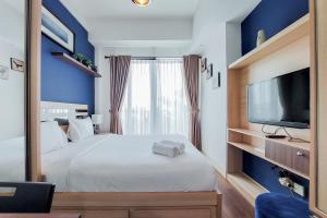 a bedroom with a large bed and a tv at Nice and Elegant Studio at Tree Park City BSD Apartment By Travelio in Tangerang +9 photos