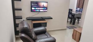 a living room with a leather chair and a tv at "Ambi's stay " A unique and Secluded Nest with serene calmness views on a Traffic-Free Street at Bommasandra 3 km from Narayana Hrudayalaya Hospital in Bangalore