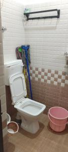 a bathroom with a toilet and a pink bucket at "Ambi's stay " A unique and Secluded Nest with serene calmness views on a Traffic-Free Street at Bommasandra 3 km from Narayana Hrudayalaya Hospital in Bangalore