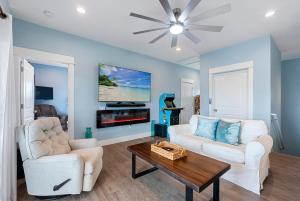 a living room with two white chairs and a table at Cape Ocean Front - Jacuzzi - Elevator - Arcade Games! in Port Saint Joe