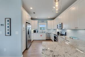 a kitchen with white cabinets and a marble counter top at Cape Ocean Front - Jacuzzi - Elevator - Arcade Games! in Port Saint Joe