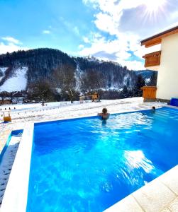 a swimming pool in the snow with a mountain in the background at Friends & Family Moieciu in Moieciu de Jos