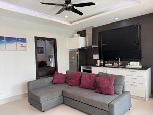 a living room with a gray couch with red pillows at Orchid Pool Villas - Koh Chang in Ko Chang