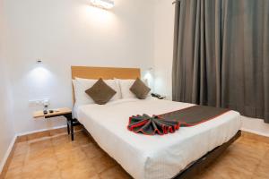 a bedroom with a large bed with a black bow on it at Magnum Resorts Candolim in Candolim