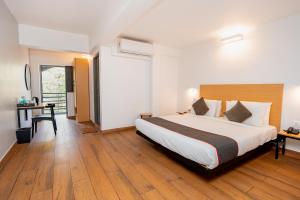 a hotel room with a large bed and a desk at Magnum Resorts Candolim in Candolim