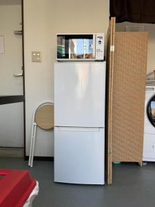 a white refrigerator with a microwave on top of it at ホステル今鶴 二人部屋 302号室 in Osaka