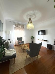 a living room with a couch and chairs and a chandelier at Lupita, apartamento en el centro de Vigo in Vigo