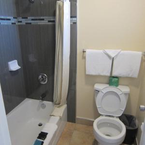 a small bathroom with a toilet and a shower at Pacific Best Inn in Seaside