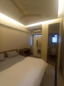 a bedroom with a white bed and a bathroom at Sheen Residences in Navi Mumbai