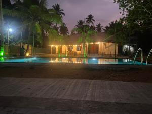a swimming pool at night with a building with lights at Dana Villa in Bentota