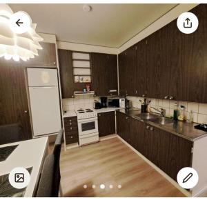 a kitchen with wooden cabinets and a white stove top oven at Spacious Northern City Apartment in Rovaniemi +17 photos