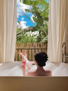 a woman sitting in a bath tub with a glass of wine at LayLa Homestay in Lạc Dương +43 photos