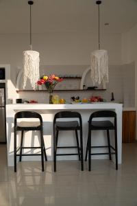 una cocina con un mostrador blanco con dos taburetes en Villa Azula Bali, en Canggu